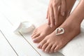 Woman applying foot cream on white wooden floor, closeup with space for text. Royalty Free Stock Photo