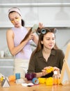 Woman applying hair rollers to friend in front to vanity mirror Royalty Free Stock Photo