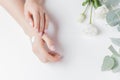 Woman applying hand cream flowers eucalyptus on white background, top view. Concept cosmetic body care, anti-wrinkles