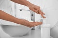 Woman applying hand sanitizer indoors, closeup. Personal hygiene during COVID-19 pandemic