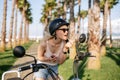 Woman applying lipstic sitting on elecrtic bicycle.