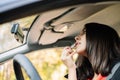 Woman applying lipstick while looking at car mirror Royalty Free Stock Photo