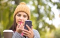 Woman applying lipstick looking at the phone like in a mirror Royalty Free Stock Photo