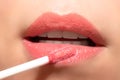 Woman applying liquid lipstick cream to her lips. Close up