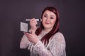 Woman applying makeup with brush holding compact mirror