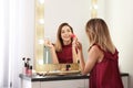 Woman applying makeup near mirror with light bulbs in room Royalty Free Stock Photo