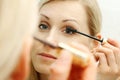 Woman applying mascara in front of mirror Royalty Free Stock Photo