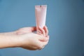 Woman applying moisturizing hand cream. Pink tube in female`s hands
