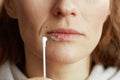 Woman applying ointment using cotton swab against beige