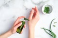 Woman applying organic moisturizer hand cream. Aloe vera lotion bottle in female hands and sliced plant stems on marble background Royalty Free Stock Photo