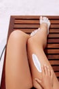 Woman applying sun protection lotion on legs. Skin care.  A Female  smear  sunscreen on beautiful legs on beach. Sun cream Royalty Free Stock Photo