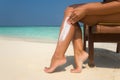 Woman applying sunblock cream on leg on beautiful tropical beach Royalty Free Stock Photo