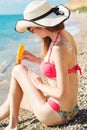 Woman applying sunscreen cream on her legs