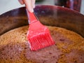 A woman applying syrup on to a half of homemade gluten-free sponge cake with a cooking brush