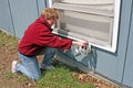 Woman applying window weather stripping in Fall