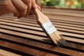 Woman applying wood stain onto planks, closeup