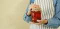 Woman in apron holds jar of pickled tomatoes