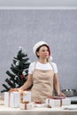 Woman in an apron and New Years hat next to gift boxes on New Year tree background. Vertical frame Royalty Free Stock Photo