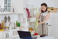Woman with notebook and phone cooks in kitchen. Isolation period, quarantine, social distancing. Remote education or remote work Royalty Free Stock Photo