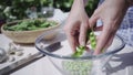 Close up of girl finger peeling hulled peas in a glass bowl outdoors sunlight