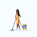 Woman in apron using vacuum cleaner african american female janitor cleaning service floor care concept flat full length Royalty Free Stock Photo