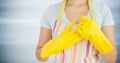 Woman in apron with yellow gloves on against blurry grey wood panel Royalty Free Stock Photo