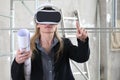 Woman architect or construction engineer wear virtual reality glasses and helmet and touch screen inside a building site with Royalty Free Stock Photo