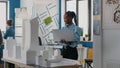 Woman architect holding laptop to analyze building model in architectural office. Royalty Free Stock Photo