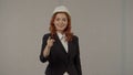 A woman architect points her index finger at the camera. Portrait of a woman in a protective helmet and business suit in Royalty Free Stock Photo