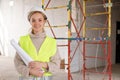 Woman architect in protective helmet with paper project on construction site