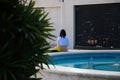 Woman architect sitting on a fountain resting and examining the plans of the houses. The woman is held from behind for the photo.