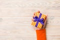 Woman arms holding gift box with colored ribbon on yellow rustic wooden table background, top view copy space Royalty Free Stock Photo