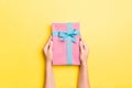 Woman arms holding gift box with colored ribbon on yellow table background, top view and copy space for you design Royalty Free Stock Photo