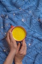 Woman arms holding mug of hot spiced winter drink turmeric golden milk