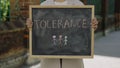 Woman arms holding and raising schoolboard with tolerance text message on street close up. Education concept.