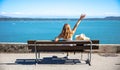 Woman arms raised on a bench in front of sea Royalty Free Stock Photo