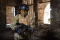 A woman in an army uniform holds a firearm in an abandoned building.