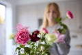 Woman Arranging Bunch Of Flowers On Kitchen Counter In New Home Royalty Free Stock Photo