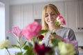 Woman Arranging Bunch Of Flowers On Kitchen Counter In New Home Royalty Free Stock Photo