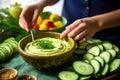 woman arranging cucumber slices around hummus bowl