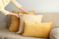 Woman arranging pillows on sofa, closeup view.