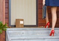 Woman arrives home after work to delivery parcel with label at door Royalty Free Stock Photo