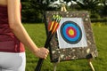 Woman with arrows near archery target in park, closeup