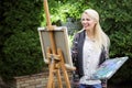 Woman artist with a brush in her hand draws on canvas Royalty Free Stock Photo