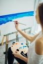 Woman artist painting a picture in a well-lit studio Royalty Free Stock Photo