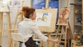 Woman artist painting watercolor picture in her studio