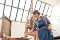 Woman artist paints a picture on canvas. Bright art studio with a large window. Easels and canvases. Royalty Free Stock Photo