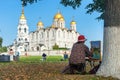 A woman artist paints a picture a holy Assumption Cathedral Orthodox church outdoors in the