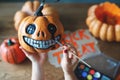 Woman artist prepares for halloween and paints pumpkins Royalty Free Stock Photo