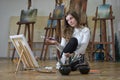 Woman artist sits on the floor in an art studio and paints on canvas Royalty Free Stock Photo